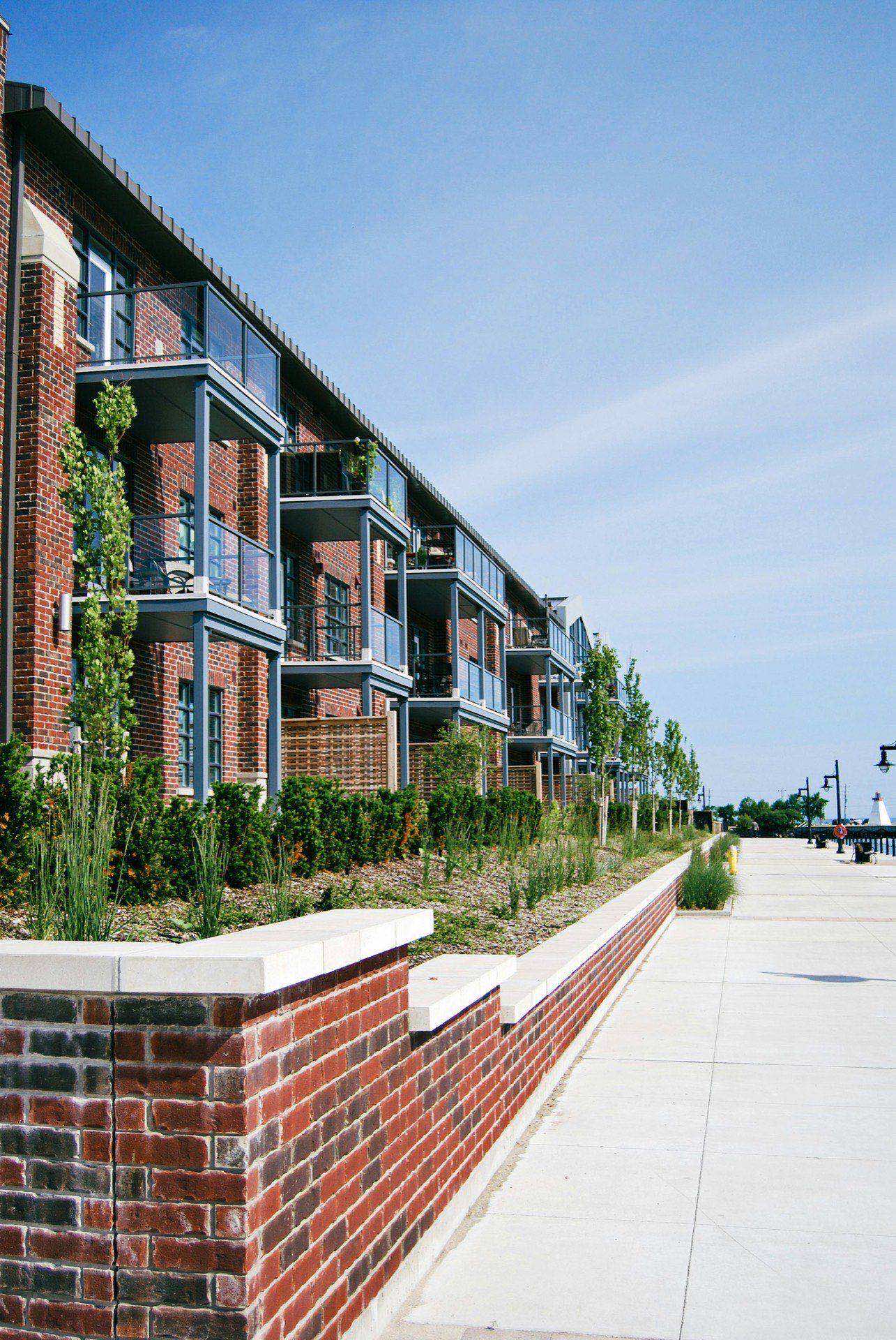 Multifamily apartment building with a brick facade and private balconies along a waterfront promenade
